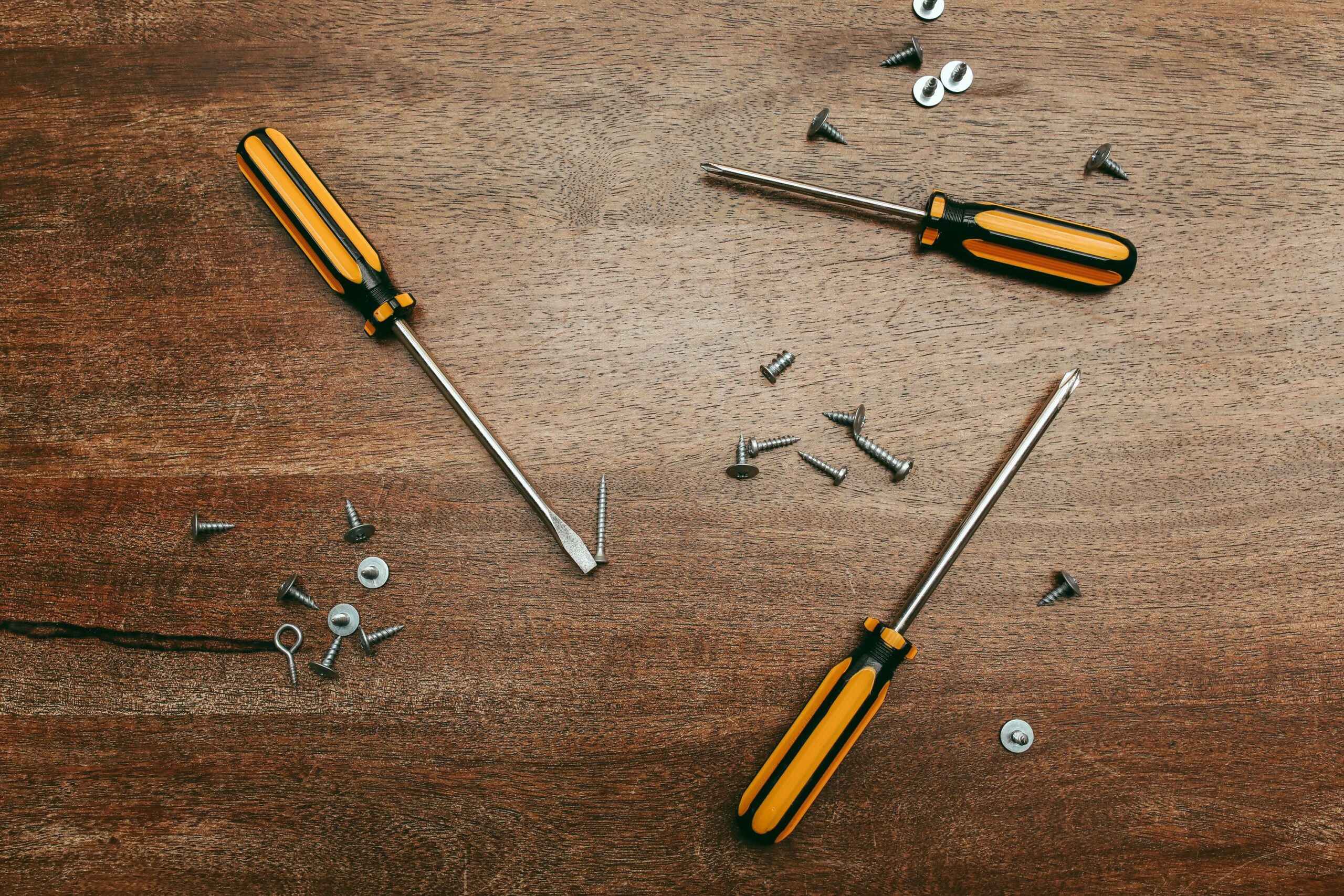 Flatlay of screwdrivers and screws on a wooden table, perfect for carpentry themes.